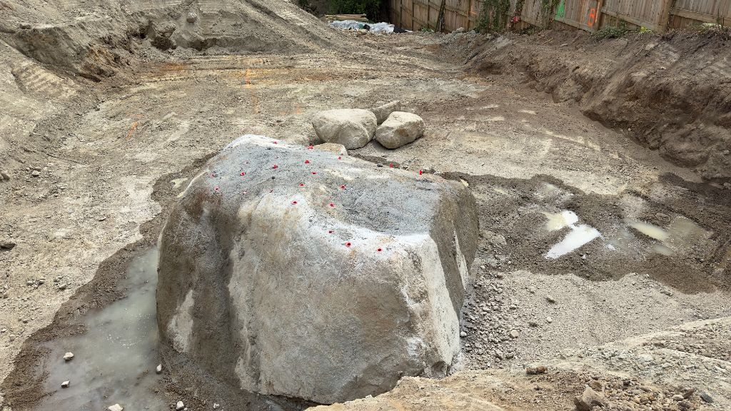 Massive boulder marked with drill pattern for alternative blasting