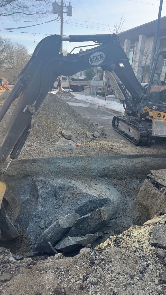 Excavator demolishing concrete in a residential winter street